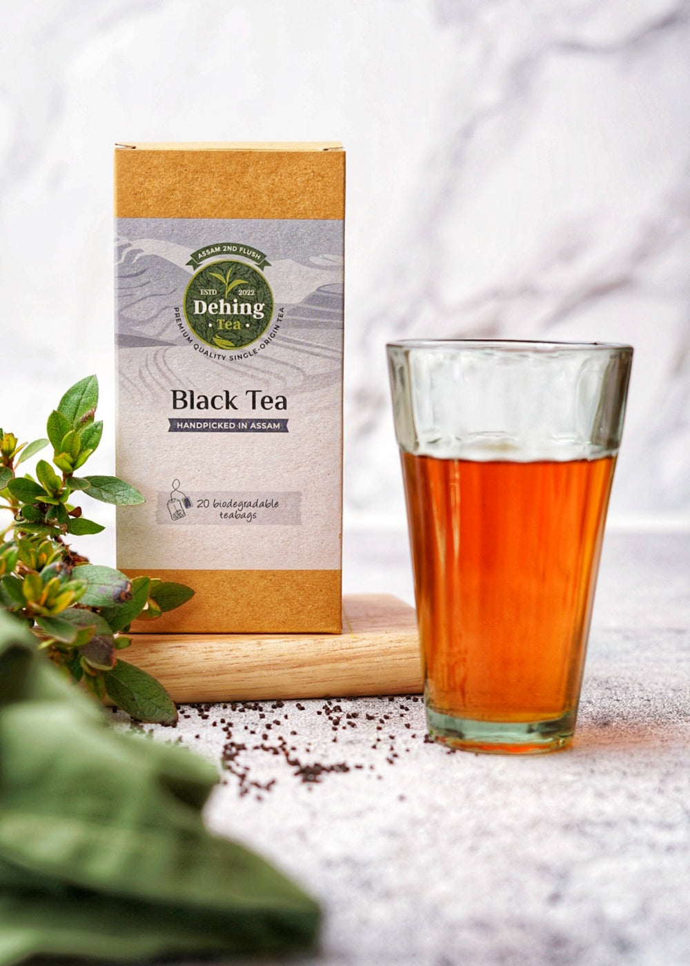 Dehing Black Tea box with a glass of tea on a light background