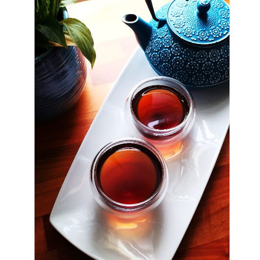 Tea pot and two cups of freshly brewed Assam tea with a deep copper colour