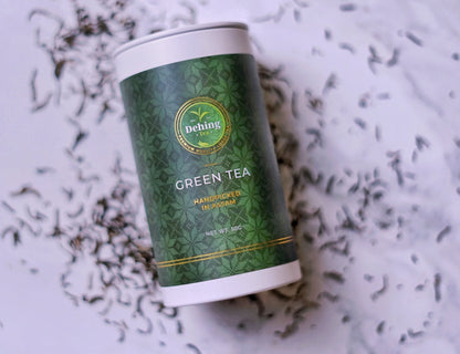 Assam green tea gift caddy canister with Dehing Tea logo on a white background with tea leaves.