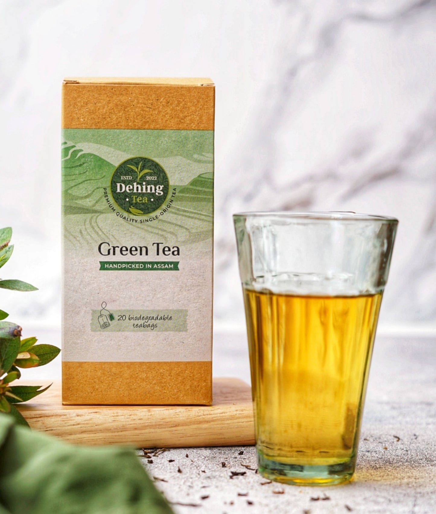 A Dehing Green Tea box of 20 biodegradable tea bags and a glass of green tea