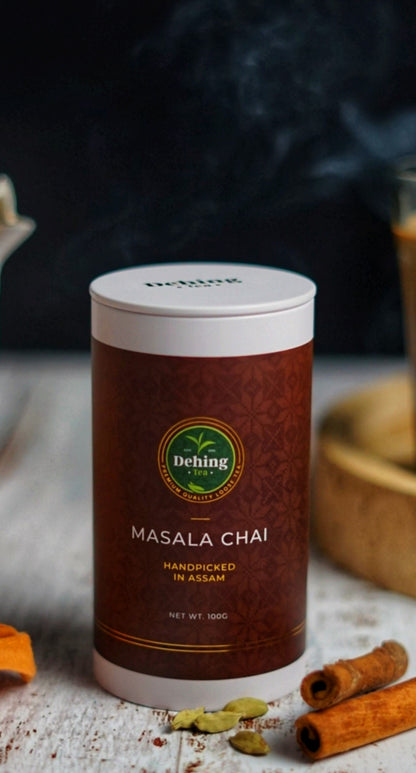 Dehing Masala Chai tea gift caddy on a rustic background with cinnamon sticks and cardamom and spices.